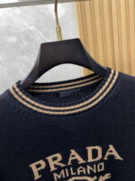 Prada wool blend knit sweater1. Wool and cashmere blended fabric:Selected high-quality wool and cashmere raw materials are blended in a certain proportion. Wool provides warmth and durability, while cashmere gives clothing a soft and delicate touch, making the fabric both comfortable and practical. Different from market products, our sweaters have a softer and more sticky texture2. Yarn preparationYarn dyeing and binding: Analyze the binding of yarn in the original version to ensure color reproduction and good color fastness.Yarn quality inspection: Conduct strict quality inspections on the yarn, including indicators such as line density, evenness, and moisture regain, to ensure that the yarn quality meets production standards.3. Knitted knittingUsing advanced knitting and weaving equipment to weave blended yarn into knitted shirts. During the weaving process, it is necessary to precisely control parameters such as knitting density and pattern changes to ensure the quality and appearance of the finished product. The precision of restoring the knight pattern4. Detail decoration and logo treatmentRibbed Knitted Decoration: Ribbed knitted decoration is used on the collar, cuffs, and hem of knitted shirts to enhance the beauty of details and make the clothing more in line with the body shape.Logo processing: Fix the Equestrian Knight logo (EKD) and Burberry lettering logo onto a knitted sweater through knitting. These logos enhance the recognition of clothing.5. Post sorting and inspectionShrinking treatment: Using the shrinking characteristics of cashmere fibers to shrink knitted sweaters.Ironing and shaping: Ironing knitwear to make it flatter, firmer, and maintain its style characteristics. Accurate temperature and pressure control is required during the ironing process to prevent clothing deformation or damage.Size: M-xxl - Image 3