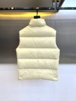 Mon蒙口（鹅绒）、2025秋冬新品 | MONCLE羽绒马甲。

米白色立领设计搭配顺滑拉链系统，正面采用100%锦纶防风面料，背面运用亮黄色轻量材质形成撞色美学。填充90%鹅绒与10%羽毛的黄金配比，绒朵蓬松度达600+FP，充绒量精准适配5℃至-5℃环境。左胸点缀经典立体刺绣徽章，两侧斜插口袋以隐藏式拉链保持流畅线条。

双面不同配色实现一衣多穿场景：米白面可搭配同色系针织衫演绎都市极简风，亮黄面翻转后瞬间提升视觉活力。立体剪裁确保活动自由度，台湾盟可睐有限公司精工制造，通过RN116347质量追溯体系。从防泼水锦纶到鹅绒填充，诠释蒙口将高山机能基因融入日常穿着的设计哲学。1-5码（模特173，143斤上身2码） - Image 8