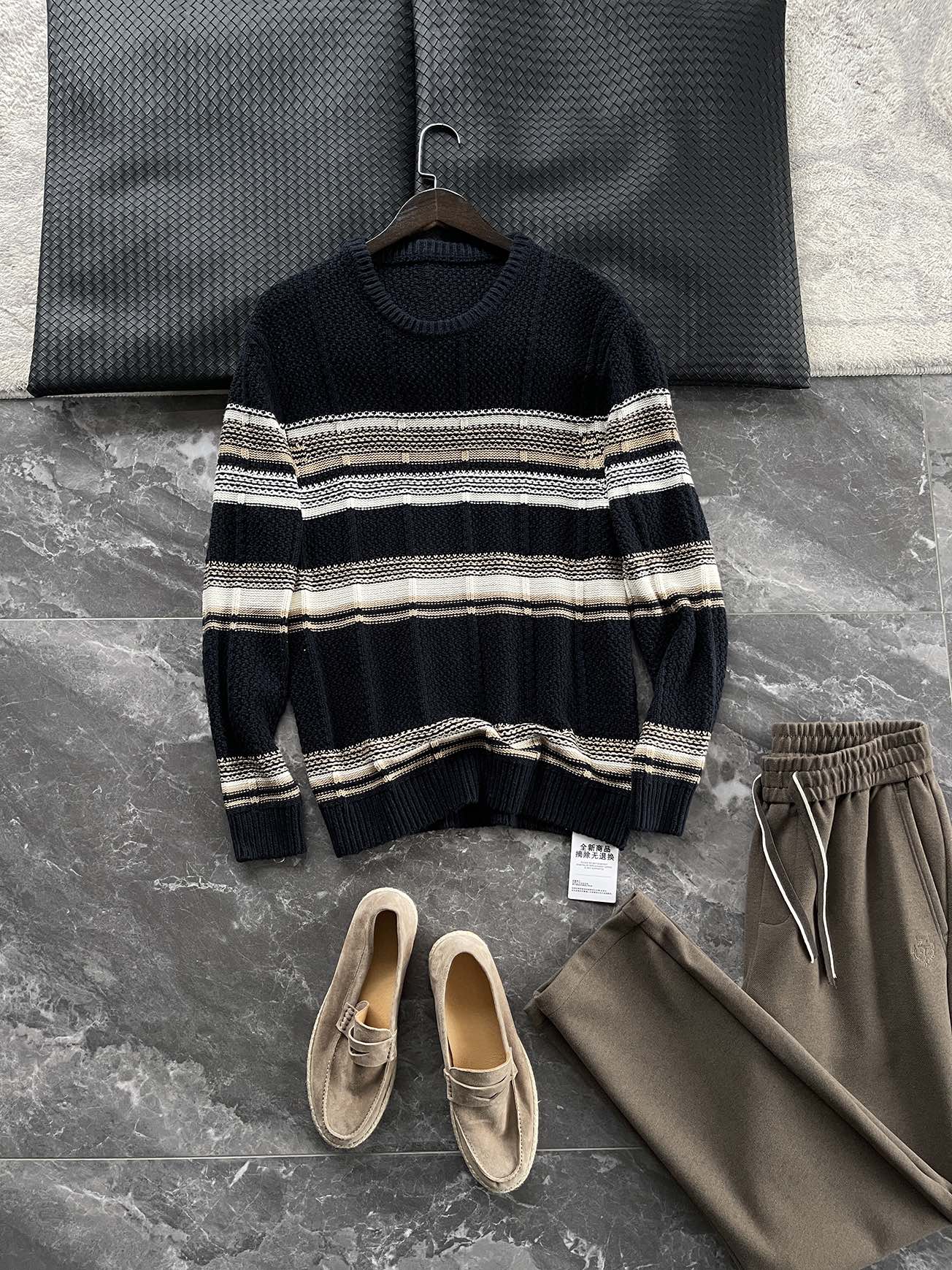 🆕- This knitted sweater weaves a Mediterranean breeze into the wardrobeWhen 10 cotton yarns and 46 blended yarns meet on a seven needle jacquard machine, the three yarns begin to weave a dialogue about material and color. Navy blue and navy blue cotton yarn have a rough and rustic feel, like the late night waters of the Adriatic Sea; The addition of 3.7% mulberry silk and wool in the light camel colored blended yarn gives the striped edges a subtle luster, reminiscent of the sparkling waves at sunset in Venice.When the weight of 580 grams is unfolded in the hand, one can feel the delicate balance between the stiffness of cotton and the softness of blended yarn. The vertical jacquard woven alternately with osmanthus needles and hanging needles forms a subtle texture on the navy blue background, resembling the outline of Venetian architecture seen through blinds. The white version is like a linen cloth sprinkled with sunlight, and the collision of the three materials is portrayed more clearly on a pure white canvas.The curvature of the round neck continues the elegant tradition of Italian tailoring, neither tightening the neck nor maintaining sharp lines. The contraction process of the hem keeps the hem of the garment firmly attached to the waist, and it will not move up whether you lift your hand or turn around. To support the muscles and bones with 10 strands of cotton yarn, to outline with delicate 46 strands of blended yarn, and to add luster and mulberry silk embellishment - this knitted sweater weaves the advantages of different materials into the same picture.The navy blue version paired with white pants is a classic Mediterranean style, while the white version paired with dark gray trousers can instantly switch to Milan style urban elegance. The intentions hidden in the texture of osmanthus needles, yarn blending, and precise weight all need to be personally felt in the cool autumn breeze to fully understand. While others are still struggling with the basic knitwear, this three layered jacquard sweater has already captivated the eyes of those who understand it with its sense of layering.In the current era of fast fashion proliferation, a blend knit that becomes softer and skin friendly with increasing wear is the truly worthwhile wardrobe evergreen tree to invest in. Jay Ya uses this piece to prove that a sophisticated sense of leisure allows every material to find the most comfortable expression in fabric.Color: White navy blue174-140 upper body size LSize: M-XXXL (48-56)Style number: FXZZ8688M size bust circumference 104 shoulder width 46.5 sleeve length 56 garment length 64.5Size L Chest circumference 108 Shoulder width 48 Sleeve length 57 Clothing length 66XL bust circumference 112 shoulder width 49.5 sleeve length 58 garment length 67.5XXL chest circumference 116 shoulder width 51 sleeve length 59 garment length 68.5XXXL bust circumference 120 shoulder width 52.5 sleeve length 60 garment length 69.5